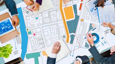 das Foto zeigt einen Tisch von oben, auf dem ein Stadtplan und Unterlagen mit daten liegen. Personen sitzen am Tisch. zu sehen sind nur deren Hände.