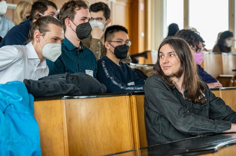 Mehrere Personen in einem Hörsaal unterhalten sich miteinander.