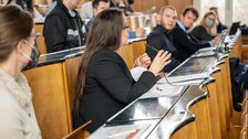 Eine Frau erklärt etwas im Hörsaal, andere schauen sie interessiert an.