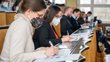 Personen sitzen im Hörsaal und machen sich Notizen.
