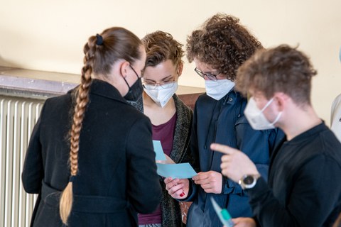 Eine Gruppe blickt auf kleine blaue Zettel und unterhält sich.
