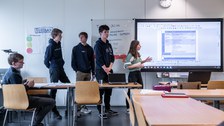 Personen halten einen Vortrag mithilfe einer Präsentation auf dem Whiteboard.