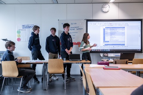 Personen halten einen Vortrag mithilfe einer Präsentation auf dem Whiteboard.