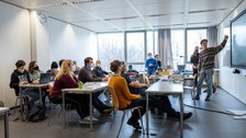 Personen präsentieren ihre Ergebnisse vor einer großen Gruppe, einige machen Notizen.