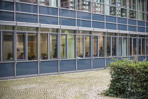 Foto der Gruppenräume von draußen fotografiert. Man sieht hinter den Fenstern einige Studierende beim Arbeiten.