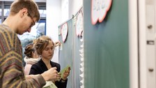 Foto von der Methode zum Abgleich der Erwartungshaltung. Studierende stehen vor einer Tafel und bekleben diese mit beschrifteten Zetteln.