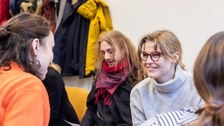Foto vom Kennenlernen der Coaches. Studierende sitzen sich in zwei Reihen gegenüber und unterhalten sich.