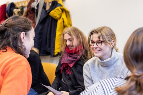 Foto vom Kennenlernen der Coaches. Studierende sitzen sich in zwei Reihen gegenüber und unterhalten sich.