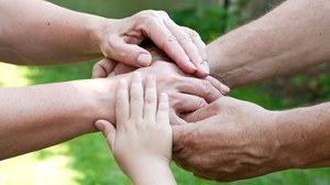 five hands on top of each other; among them hands of children and of elderly persons