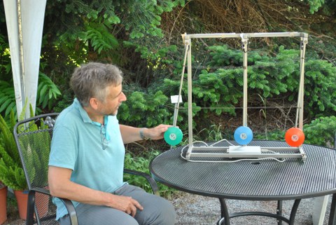 Dr. Michael Kobel setzt ein Pendel, das mit zwei weiteren Pendeln gekoppelt ist, in Schwingung.