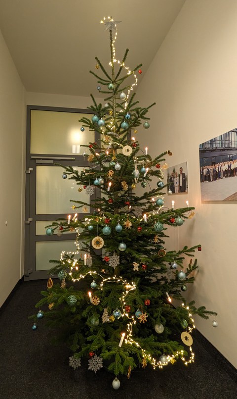 Ein reich geschmückter Tannenbaum steht in einem Büroflur.