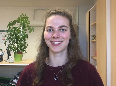  Kollegiatin Sophie Jacobs steht lächelnd in einem Büro der Professur