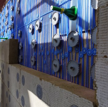 Detailed view of the gable end showing scaffolding anchors (green), a capillary drain mat, anchor washers, and an installed mineral wool insulation system