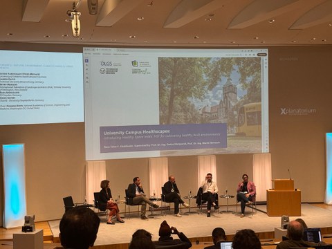 Auf dem Foto sind fünf Personen bei einer Podiumsdiskussion der IUHS 2025 zu sehen. 