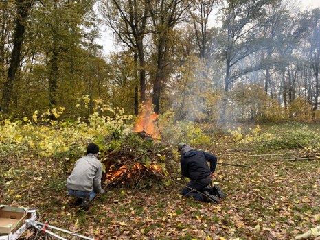 Zwei Studierende entfachen ein Feuer.