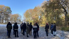Die Studierenden beim Abschlussrundgang durch den Park, auf der großen Wiese stehend.