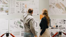 Rückenansicht zweier Personen vor ausgehängten Planen