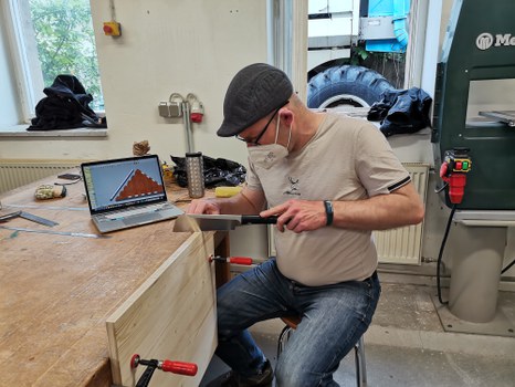 Detailfoto eines Holzelementes im Bauprozess mit Student und Werkzeug
