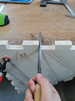 Detailfoto eines Holzelementes im Bauprozess mit Hand und Werkzeug