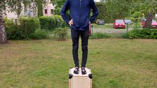 Sitzmöbel mit Student, welcher auf dem Würfel steht