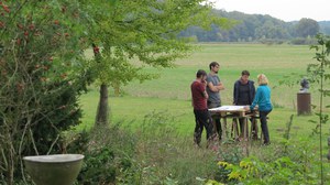 Foto von vier Personen auf einer Wiese, die an einem Tisch arbeiten