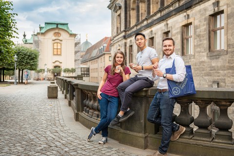 Drei TU Studenten lehnen und sitzen an einem Geländer in der Dresdner Altstadt.