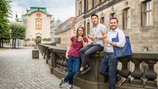 Drei TU Studenten lehnen und sitzen an einem Geländer in der Dresdner Altstadt.