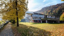 Das Foto zeigt die Rückseite des Judeich-Baus in Tharandt. Auf der großen Wiese im Vordergrund liegt Laub. Am linken Bildrand verläuft ein Bach.