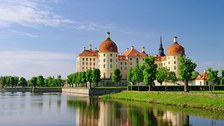 Das Foto zeigt das Schloss Moritzburg bei Dresden im Sommer. Im Vordergrund befindet sich ein See.