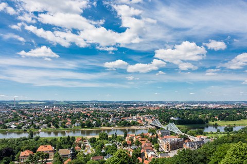 Das Foto zeigt eine Luftaufnahme der Stadt Dresden. Auf dem Foto erkennt man das Blaue Wunder und die Elbe.