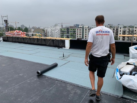 Ein Handwerker verarbeitet Schweißbahnen auf einem Flachdach.