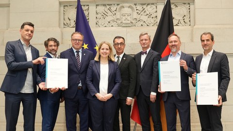 Bundesministerin Verena Hubertz u.a. mit den Ministerpräsidenten Cem Özdemir und Mario Vogt sowie den Vertretern der der Forschungseinrichtungen im Foyer des Bundesrates