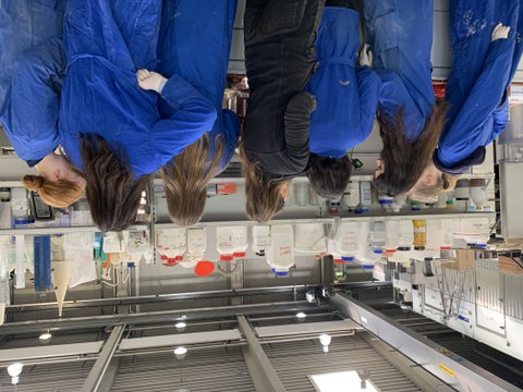Eine Gruppe Schülerinnen in blauen Arbeitsmänteln
