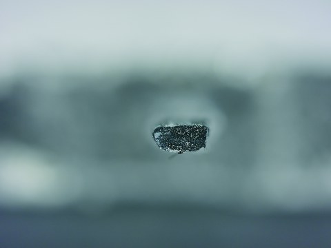 Querschnitt eines ungleichmäßig getränkten Carbonrovings, zu sehen an den Ansammlungen der polymeren Tränkung (graue Bereiche), was zu erhöhter Wasseraufnahme führt
