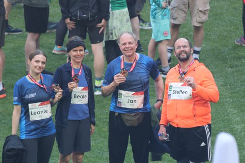Das Mixed-Team des IMF nach dem Lauf. Alle 4 Teilnehmenden halten ihre Medallien hoch.