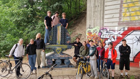Gruppe von Studierenden und Lehrenden mit Fahrrädern unter einer Brücke