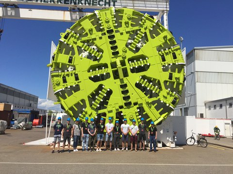 Group photo in front of a Tunnel drilling machine of the manufacturer "Herrenknecht" with a diameter of nearly six times the length of a human
