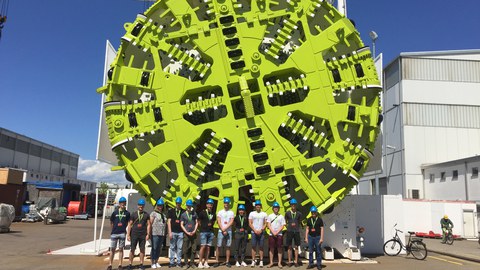 Group photo in front of a Tunnel drilling machine of the manufacturer "Herrenknecht" with a diameter of nearly six times the length of a human