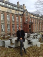 Foto vom Leiter der Einrichtung sitzend auf einem Sitzblock vor dem Hintereingang des Beyer Baus.