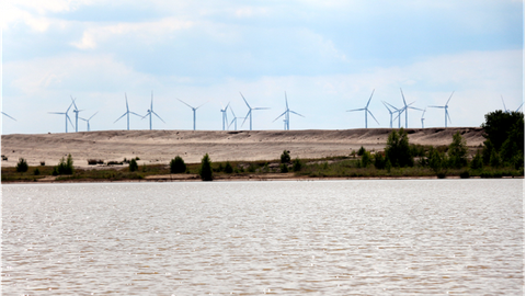Gefluteter Tagebaurestsee mit Windenergie im Hintergrund