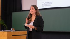Rednerin steht auf der Bühne und spricht ins Mikrofon