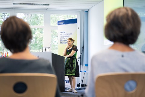 Prof. Dr. Angela Francke is delivering an engaging speech at SC92. She is wearing a green and black Bavarian dirndl, reflecting the cultural diversity showcased by some participants through their clothing.