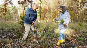 Mann mit Spaten und Frau mit kleinen Fichten beim Pflanzeinsatz