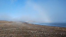 Herbsttag in Nordgrönland. Die Sonne zeichnet einen Nebelbogen auf den leichten Nebel. 