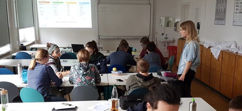 Personen sitzen in Gruppen an Tischen zusammen