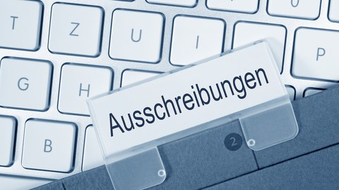 Foto zeigt eine Tastatur, auf der ein Ordner liegt zum Thema "Ausschreibungen".