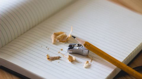 Gespitzter Bleistift liegt auf einem Heft