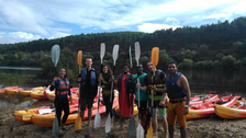 Students with Kayaks and corresponding outfits standing at the ocean somewhere in Portugal.