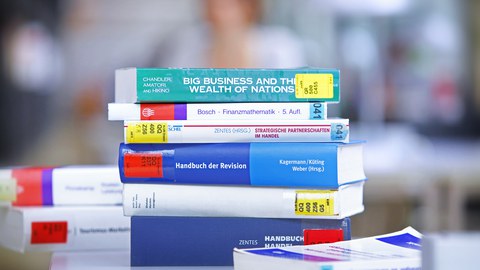 Ein Stapel Bücher liegt auf einem Tisch in der Bibliothek.