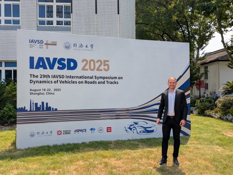 Tobias Schramm steht vor einer Tafel der IAVSD Konferenz in Shanghai